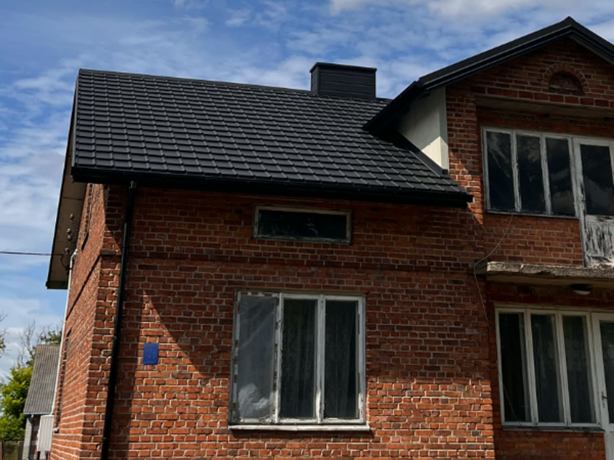 Ten sam dom po remoncie: nowe ciemne pokrycie i obróbka komina